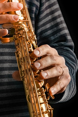 Obraz premium soprano saxophone in the hands of a guy on a black background