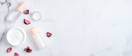 Natural organic beauty products on marble background. Top view moisturizing hand cream, essential oils and pink petals. Hand skin care concept
