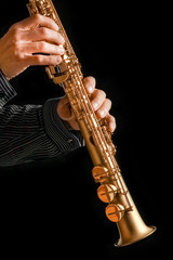 soprano saxophone in hands on a black background