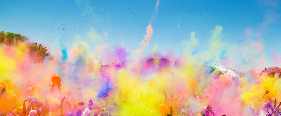 Crowd throwing bright colored powder paint in the air at Holi Festival Dahan