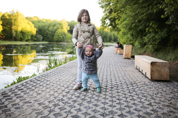 Girl leads hands little sister in park, outside