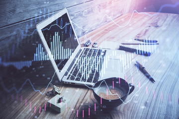 Double exposure of graph and financial info and work space with computer background. Concept of international online trading.
