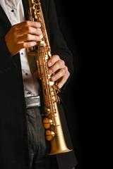 Fototapeta na wymiar soprano saxophone in the hands of a guy on a black background