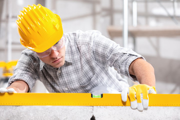 Builder or engineer in a hardhat using a spirit level on a construction site