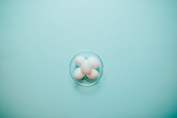 Happy Easter card with copy space. White eggs in glass plate on blue background.