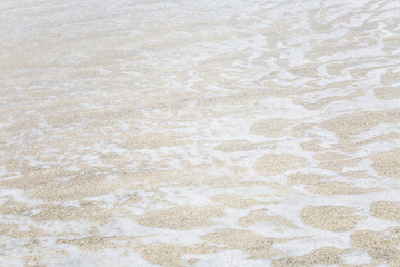 Foamy surface of a sea wave on a sandy beach. Close-up. Background. Space for text.