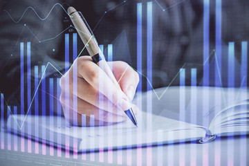 Double exposure of woman's hands making notes with forex graph hologram. Concept technical analysis.