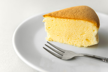 Close-up piece of egg cake and silver stainless steel fork on a white plate with white isolated background.