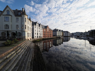 Fototapeta na wymiar Colored secessionist buildings reflected in water in european Alesund town at Romsdal region in Norway
