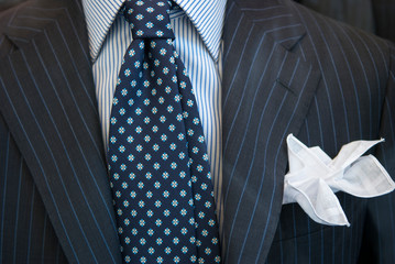 Close up of unrecognizable businessman in striped suit and shirt with patterned blue tie and white...