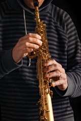 Obraz premium soprano saxophone in the hands of a guy on a black background