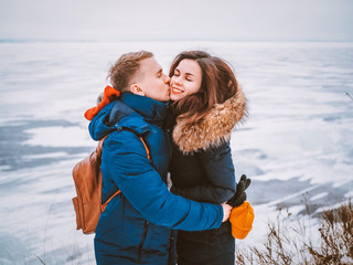 A blond man kisses a brunette girl on the background of an Icy landscape, blue mountains in the...