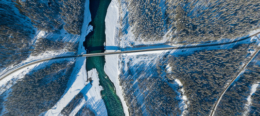 Panoramic aerial view nature and picturesque landscape near a Altay mountain with a green river Katun and bridge on a winter sunny day with blue sky © Aleksandr Kondratov