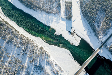 Panoramic aerial view nature and picturesque landscape near a Altay mountain with a green river Katun and bridge on a winter sunny day with blue sky