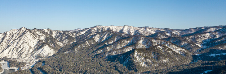 Picturesque panoramic landscape in the Altai mountains with snow-capped peaks under a blue sky with clouds in winter. White snow and calm.