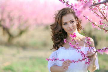 Woman in nature in a beautiful white dress in a garden with trees.