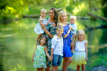 Two mothers with children in the forest near the river.