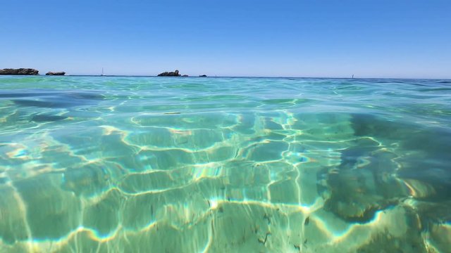 fresh clear water of the Indian Ocean rocks at the horizon and camera halfway underwater