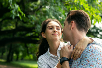 portrait smiling young man and woman couple in love hugging in the park at summer season with warm sunlight. people and lifestyle concept.