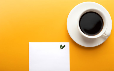 Empty sheet of paper notepad and a cup of coffee on a yellow background with copy space. Planning concept, morning, list. Mockup