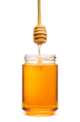 Honey wooden dripper above glass jar, on white background