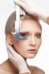 fashionable blonde female face isolated on white background, doctor's hands wearing latex gloves...