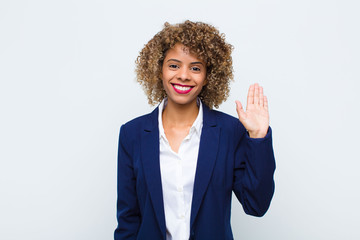 young woman african american smiling happily and cheerfully, waving hand, welcoming and greeting...
