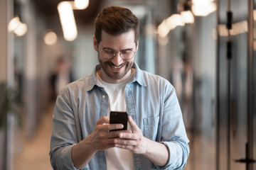Smiling male employee using modern smartphone texting