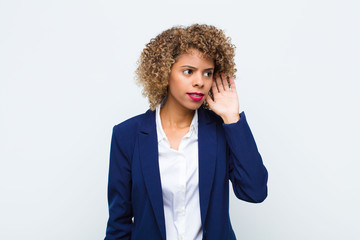young woman african american looking serious and curious, listening, trying to hear a secret...