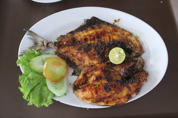 Grilled fish with vegetables on a white plate