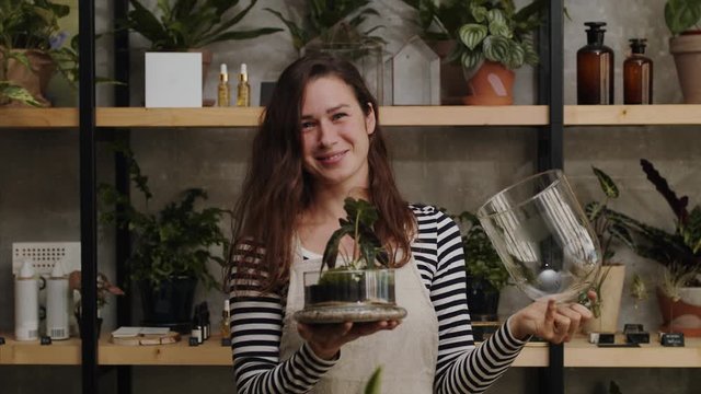 Woman florists with terrarium working in flower and plant shop.