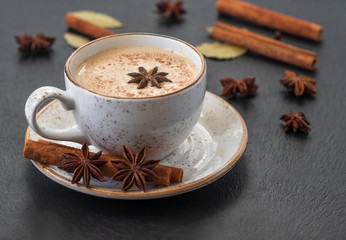 Indian Masala chai tea. Traditional Indian hot drink with milk and spices on dark stone background...