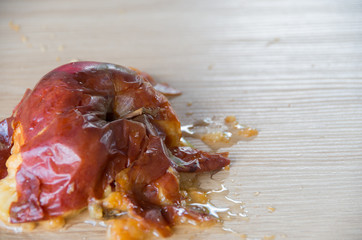 Old squuashed rotten apple isolated on a wooden bench top
