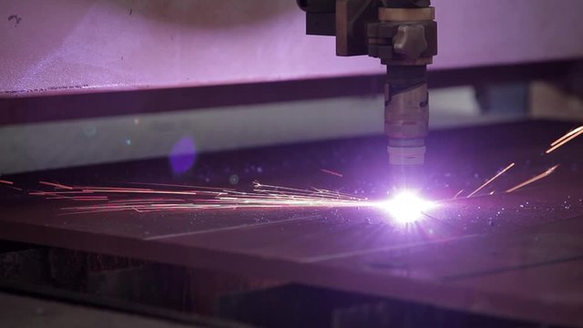 close up of robotic high energy steel cutter cutting through deep steel plates - boat factory setting