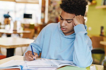 Smiling african bot teenager studying while sitting at the hub