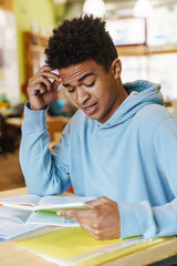 Smiling african bot teenager studying while sitting at the hub