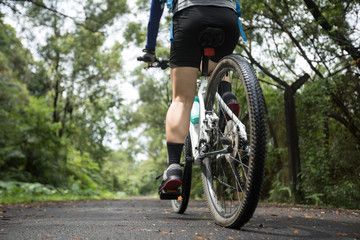 Fototapeta na wymiar Woman cyclist riding mountain bike on tropical rainforest trail