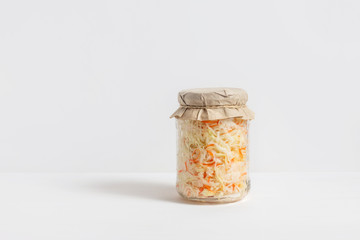 Homemade sauerkraut. Fermented food. Sauerkraut with carrots in a glass jar on a white wooden background