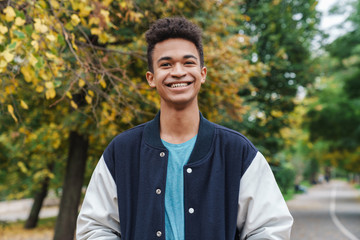 Cheerful african boy teenager walking at the park