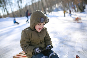 Fototapeta na wymiar Boy sledding on the street in the snowy winter in the mountains.
