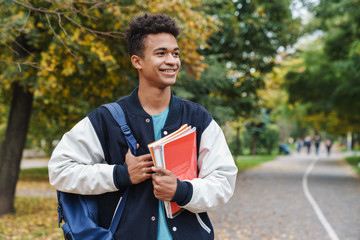 Cheerful african boy teenager walking at the park