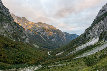 Fototapeta premium Morning sun illuminating a lush mountain valley.