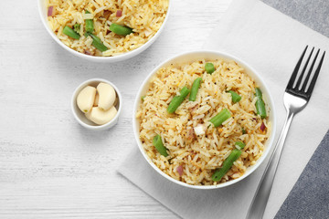 Tasty rice pilaf with vegetables served on white wooden table, flat lay