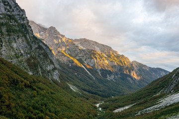 Obraz premium Morning sun illuminating a lush mountain valley.