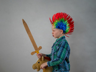 happy boy in plaid shirt is rolling on rocking horse toy. baby with wonderful punk-style colored...