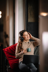 Young woman drinking coffee and listening music. Businesswoman working from home. 