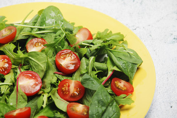 A plate with green salad and cherry tomatoes	