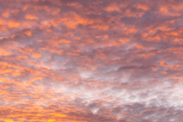 horizontal sky background during a fiery sunrise with cumulus clouds and warm colors