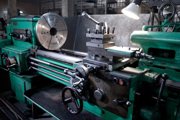 closeup of metallic lathe working against factory industrial interior background