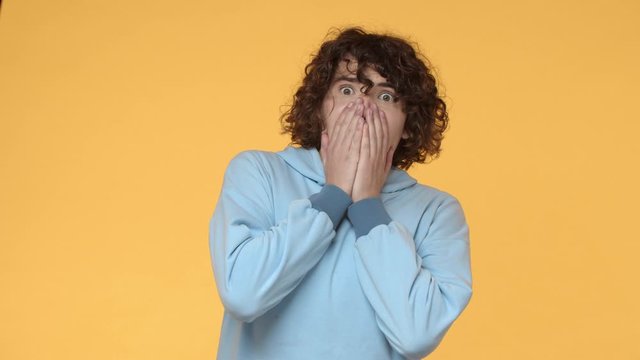 Emotions, shocking surprise. Slow-motion shocked speechless and concerned young curly man seeing something terrible, gasping, popping eyes at camera, hold hands on mouth overwhelmed